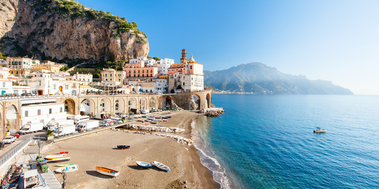 Atrani con la spiaggia incastonata tra archi di pietra e case colorate