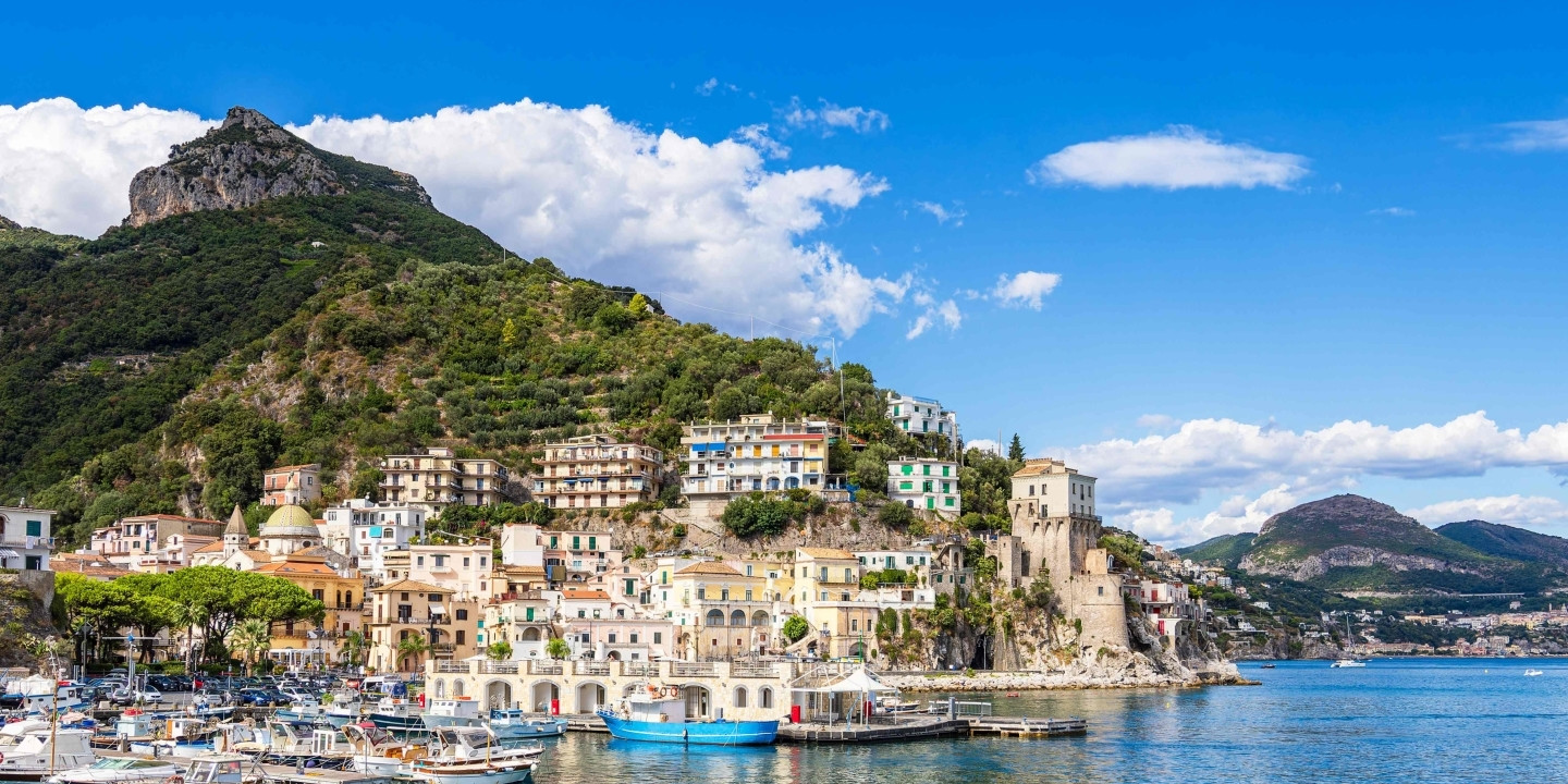 Panoramic view of Cetara harbor with boats, the colorful village, and the historic tower along the Amalfi Coast.