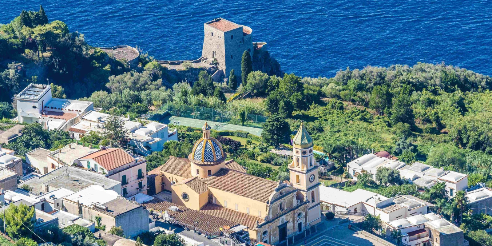 Aerial view of Praiano featuring San Gennaro Church and the medieval Torre di Grado tower overlooking the sea.