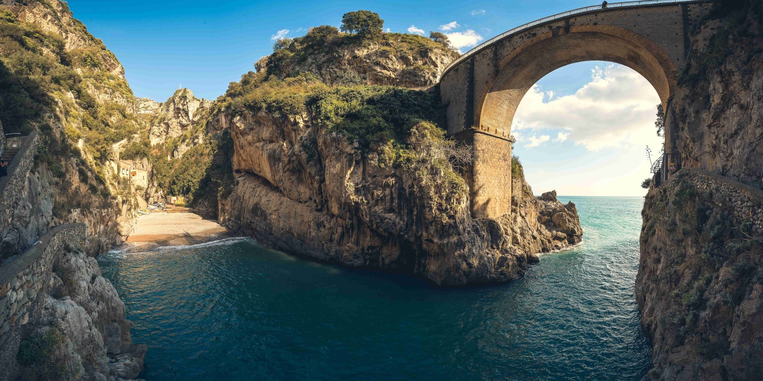 Il celebre ponte ad arco che sovrasta la spiaggia del Fiordo di Furore, incastonato tra le scogliere della Costiera Amalfitana.