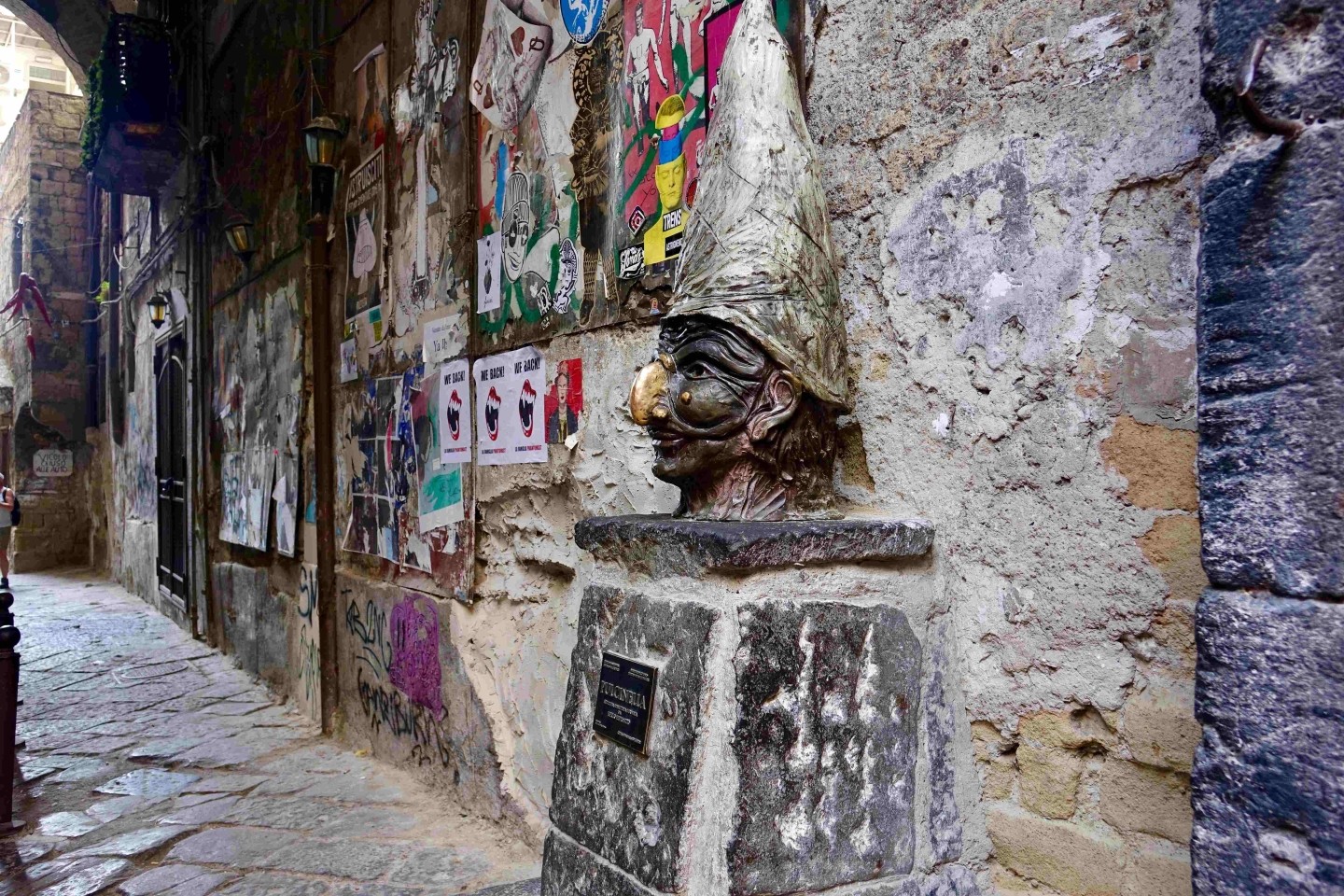 Statua di Pulcinella in uno stretto vicolo del centro storico di Napoli