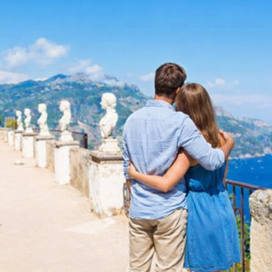 Couple embracing on a panoramic terrace in Ravello during a romantic Amalfi Coast tour with views over the sea and historic gardens.