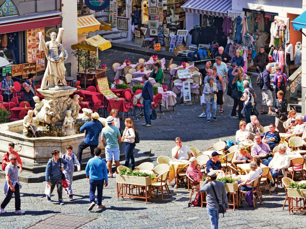 Tourists walking in Piazza Duomo Amalfi with cafes, shops and Saint Andrew fountain in Italy