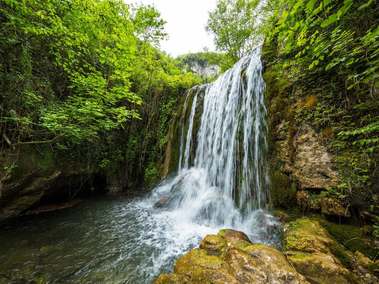 Hidden beach on the Amalfi Coast surrounded by cliffs with boats and crystal clear water in southern Italy