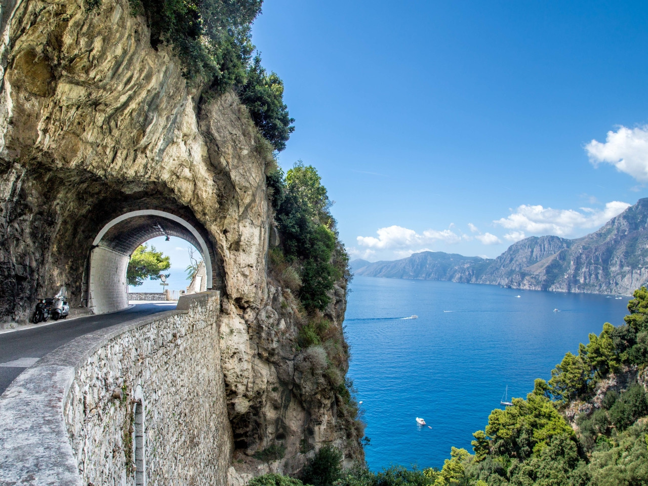 Scenic coastal road of the Amalfi Coast passing through a cliff tunnel overlooking the sea