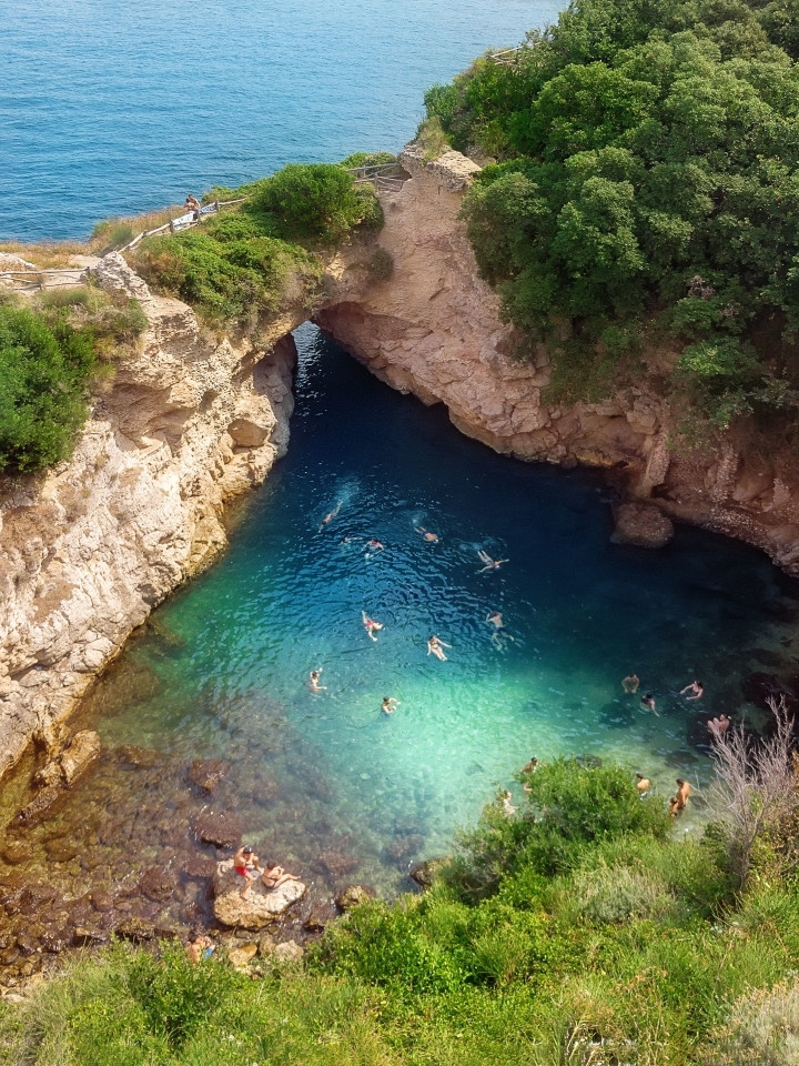 Adventurous explorers swimming in the natural pool of Bagni della Regina Giovanna in Sorrento.