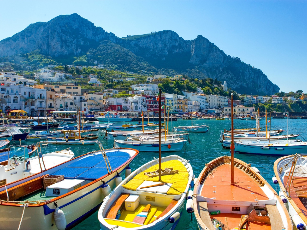 Marina Grande harbor in Capri with colorful traditional boats and mountain backdrop