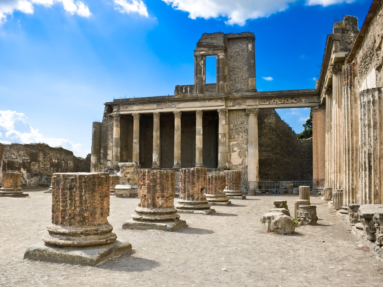 Ruins of the Basilica in Pompeii with brick arches and marble columns