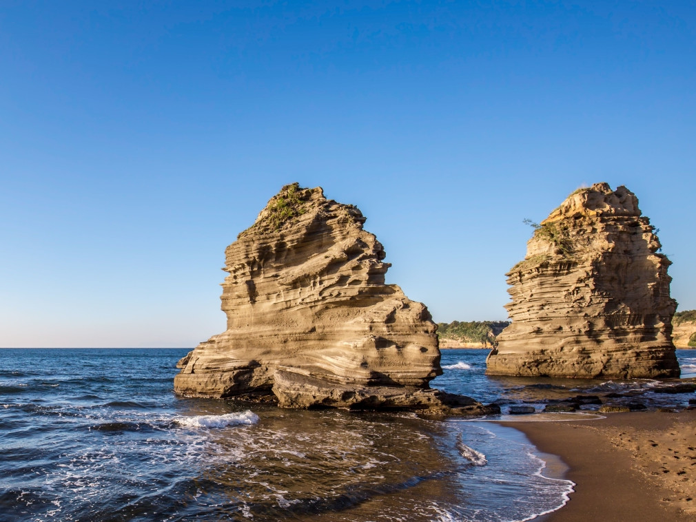 Faraglioni e spiaggia sull’isola di Procida con mare cristallino e paesaggio costiero della Campania.